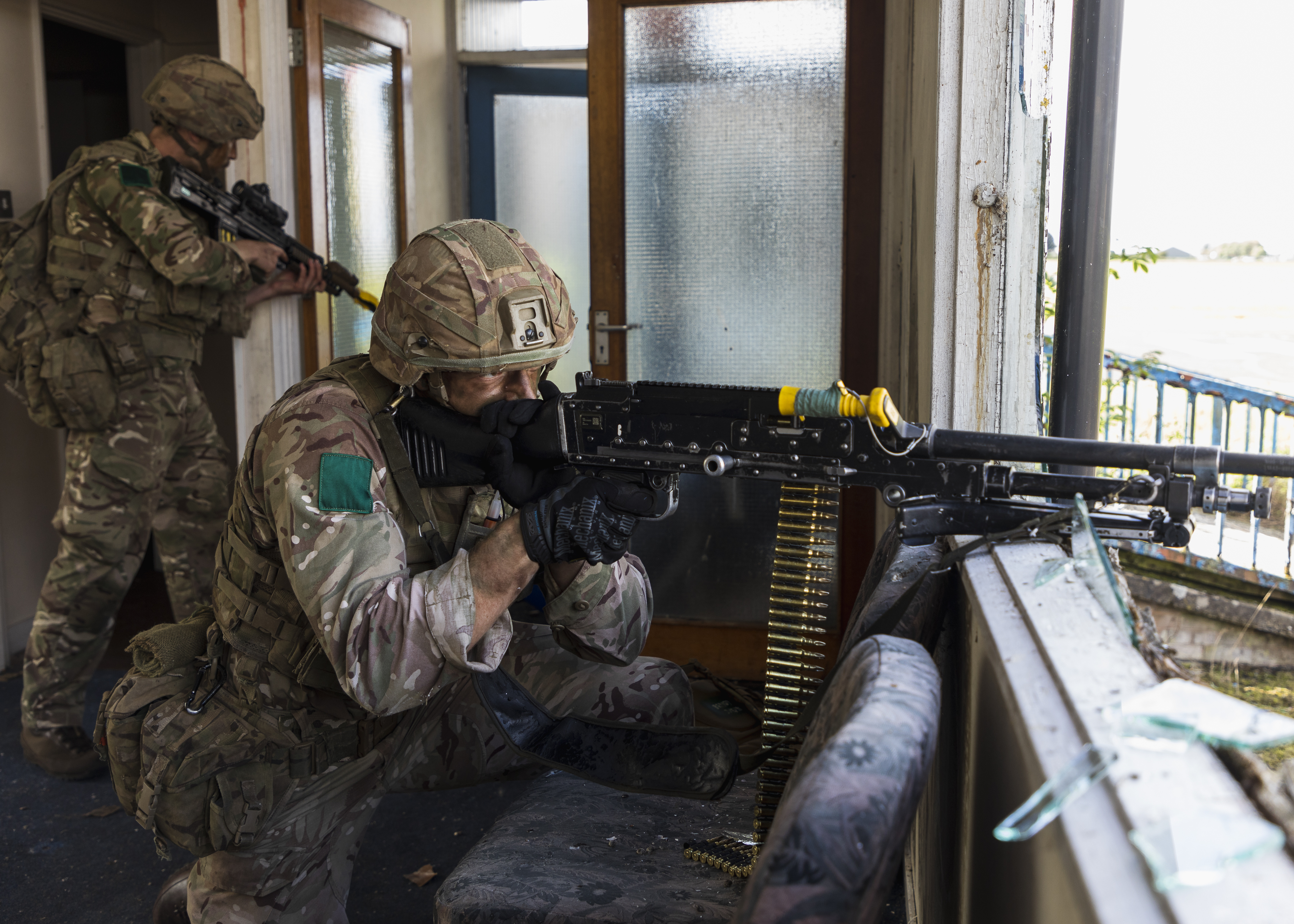 Image shows RAF personnel looking out of building with heavy machine gun and rifles..